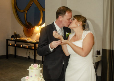 bride and groom kissing with cake